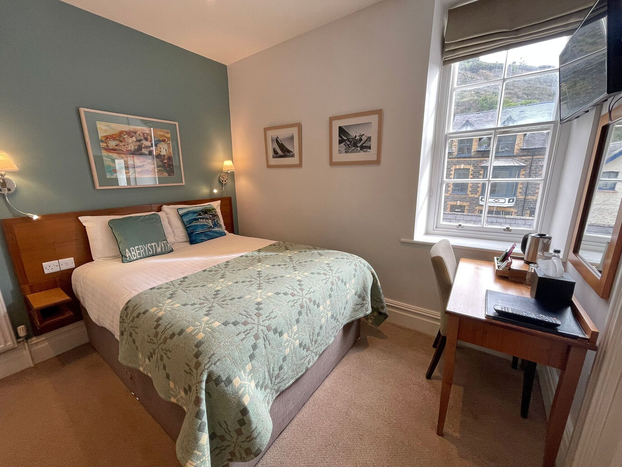 Een slaapkamer met een bed, nachtkastjes, een bureau en een raam.