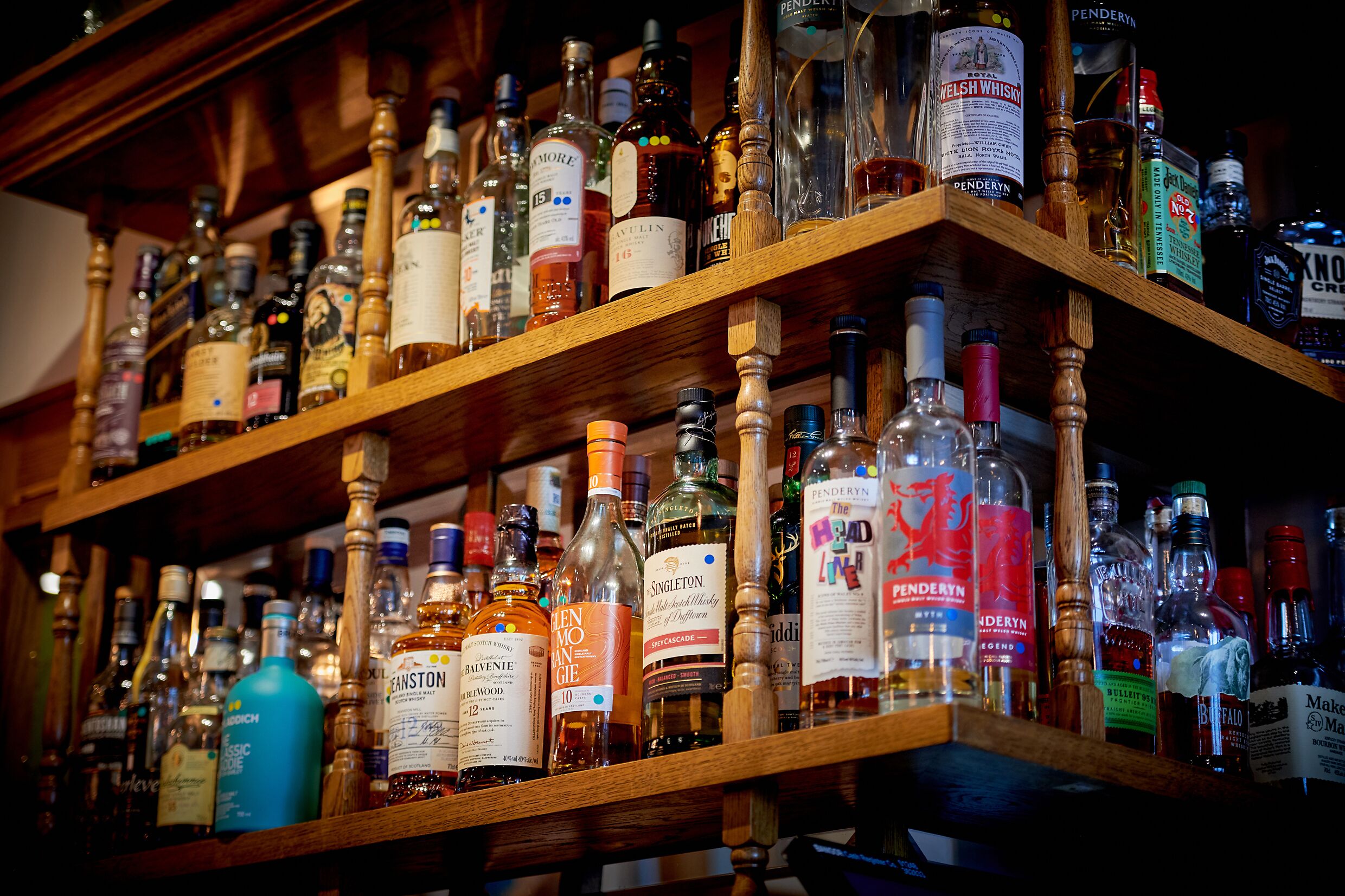 A shelf with various bottles of alcohol, including whiskey and other spirits.