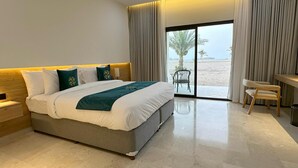 Una habitación de hotel moderna con una cama grande, un escritorio y vistas a la playa.