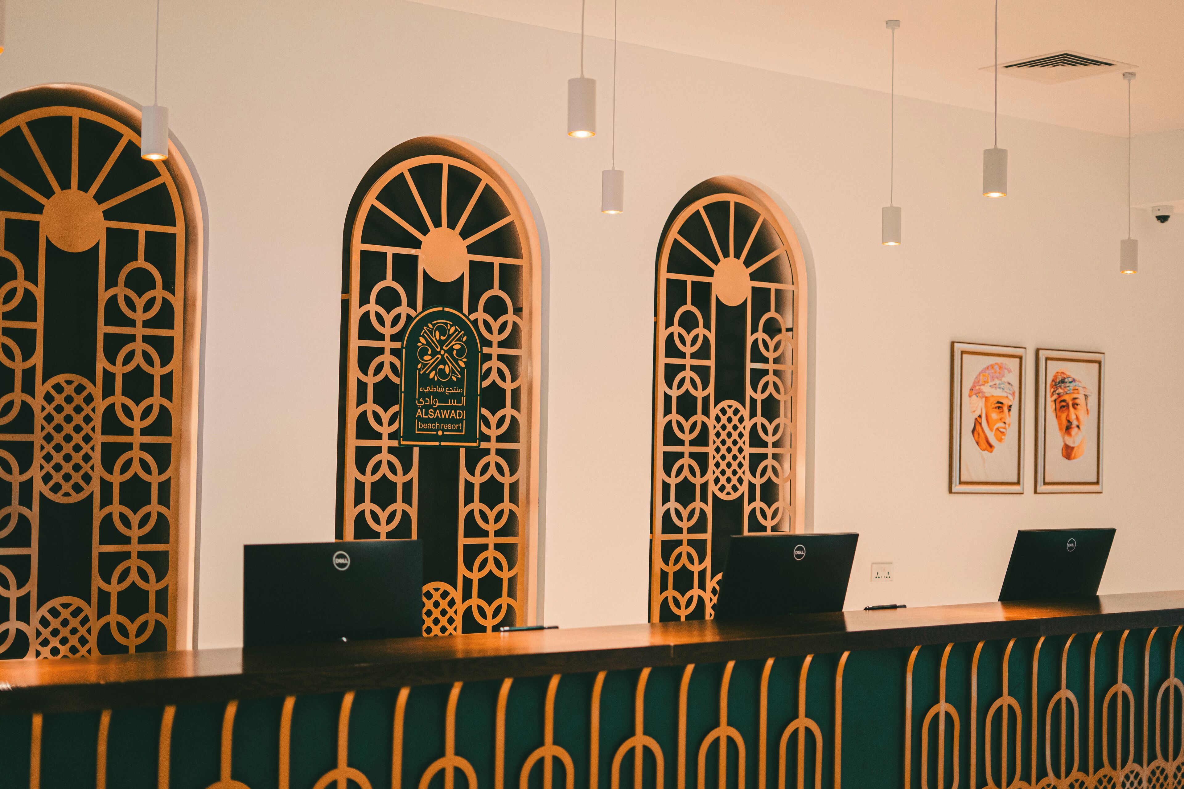 A reception area with two laptops on a counter, decorative wooden panels, and framed artwork on the wall.