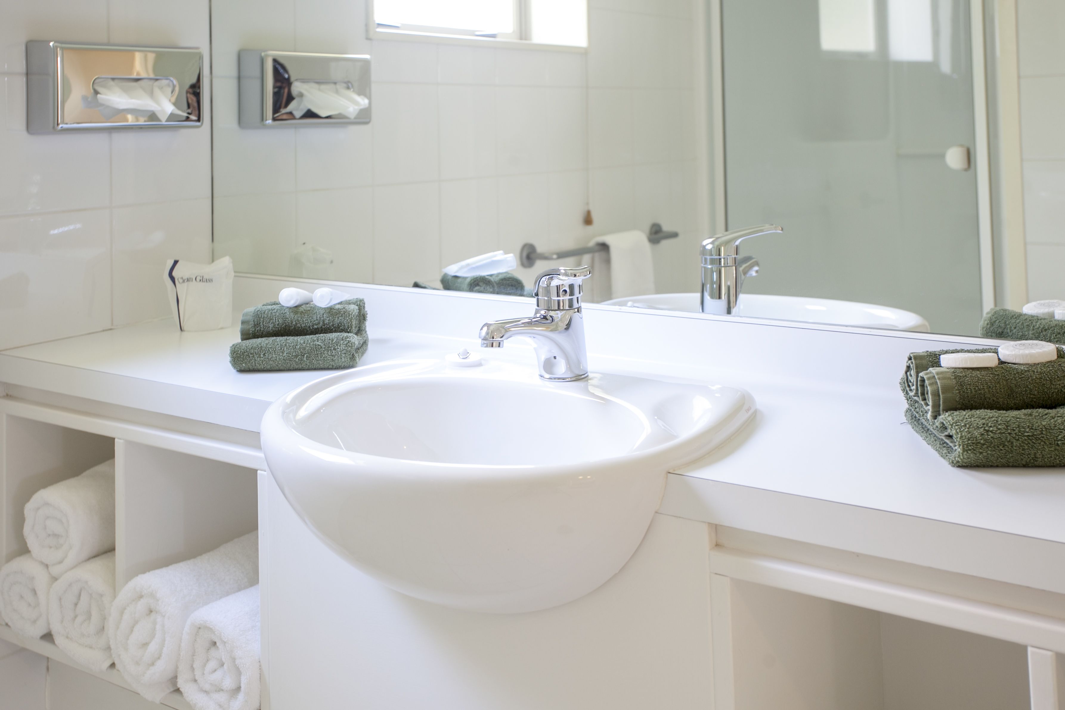 A modern bathroom with a white sink, two mirrors, and neatly folded towels.