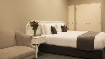 A hotel room with a bed, a nightstand, a vase with flowers, and a couch.