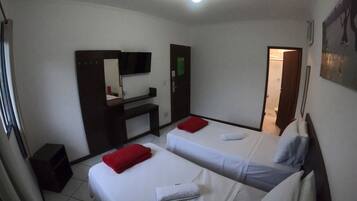 A hotel room with two beds, a desk, a TV, and a bathroom visible through an open door.