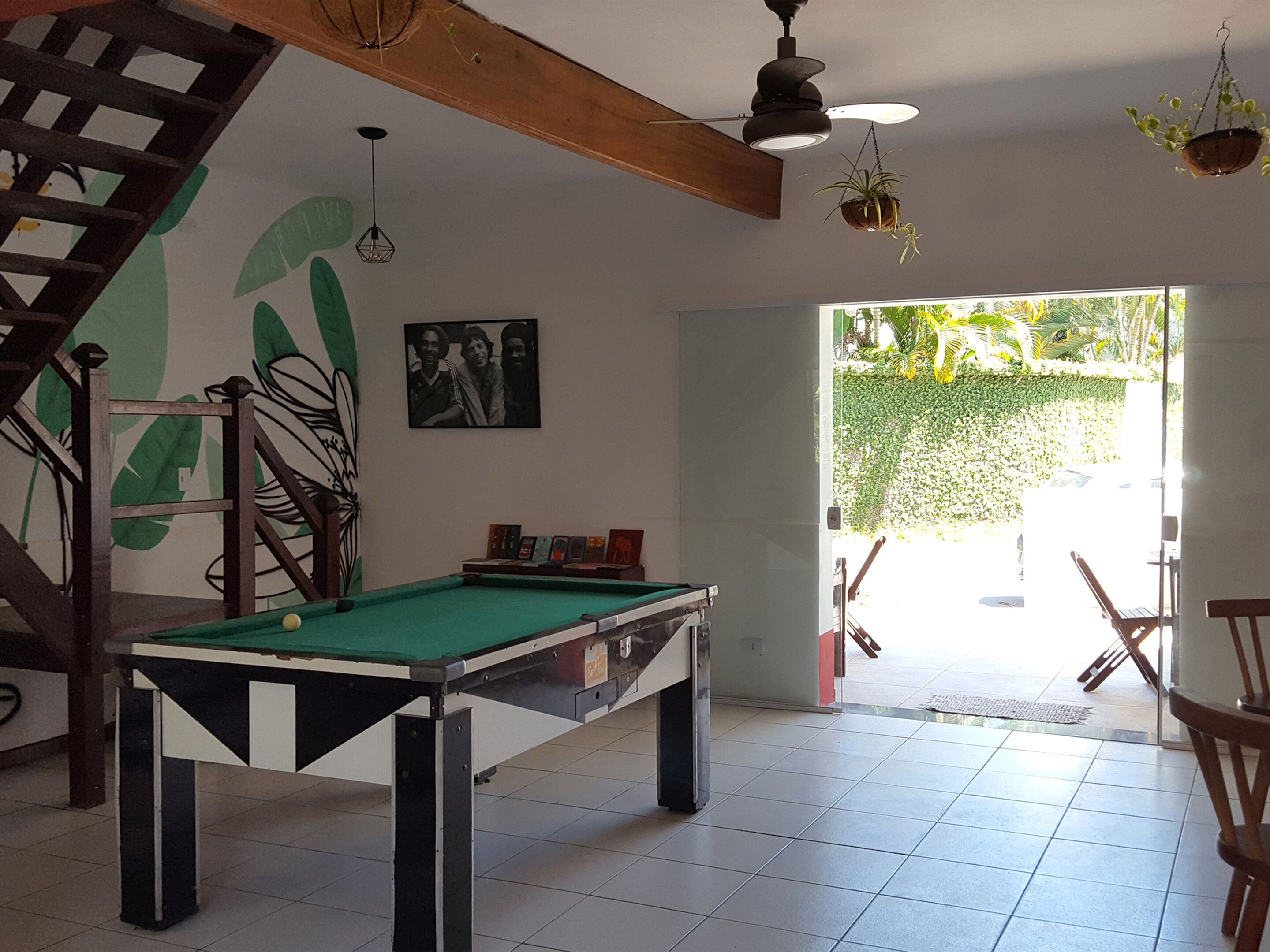 A pool table in a room with a wooden ceiling, a staircase, and a door leading outside.