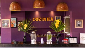 A reception area with a purple wall, three wicker pendant lights, and a sign reading "COZINHA". - Che Lagarto Paraty - Hostel (Paraty)