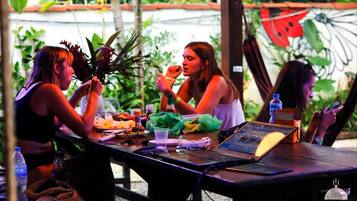 Un grupo de personas cenando en una mesa al aire libre, con una computadora portátil, botellas de agua y un menú.