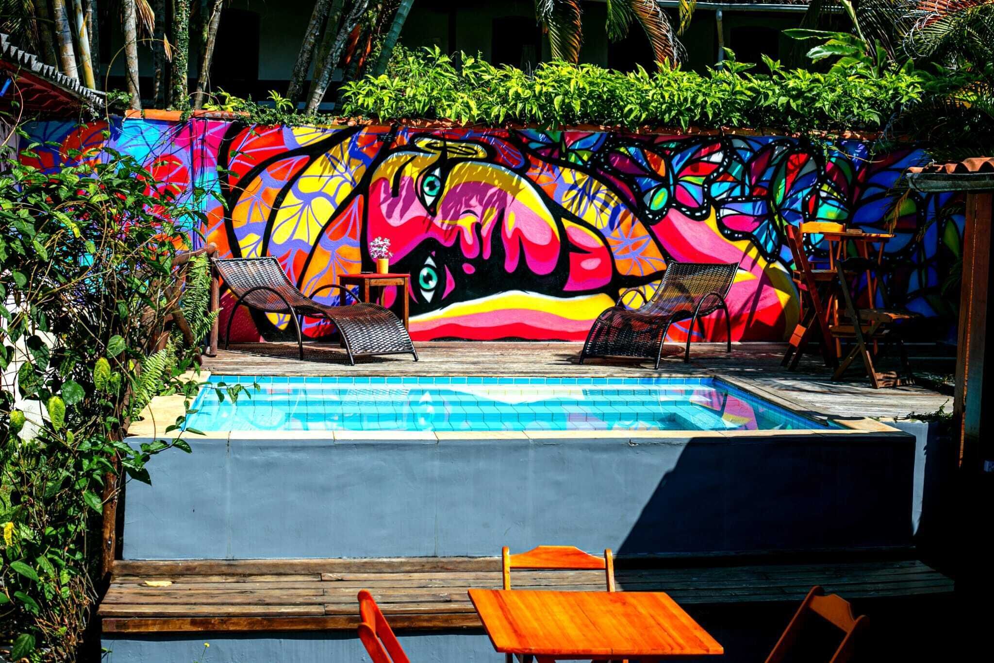 A pool area with colorful murals, lounge chairs, and a wooden deck.
