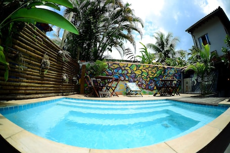 Una piscina al aire libre, sombrillas, sillones reclinables de piscina