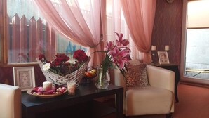 A cozy room with a wicker basket filled with red roses and pink lilies, a vase with flowers, and a candle on a dark wooden table. - La Casa (Bucharest)