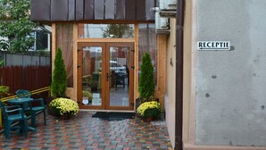 A hotel entrance with a reception desk, outdoor seating, and a tiled patio. - La Casa (Bucharest)