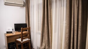 A room with a wooden desk, a chair, a television, and an air conditioning unit. - La Casa (Bucharest)
