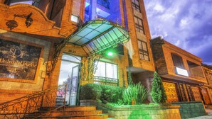 Entrada de un hotel con una escalera, un área techada y fachada de edificio con un letrero.