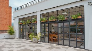 Un edificio con amplios ventanales, plantas en macetas y suelo de baldosas.
