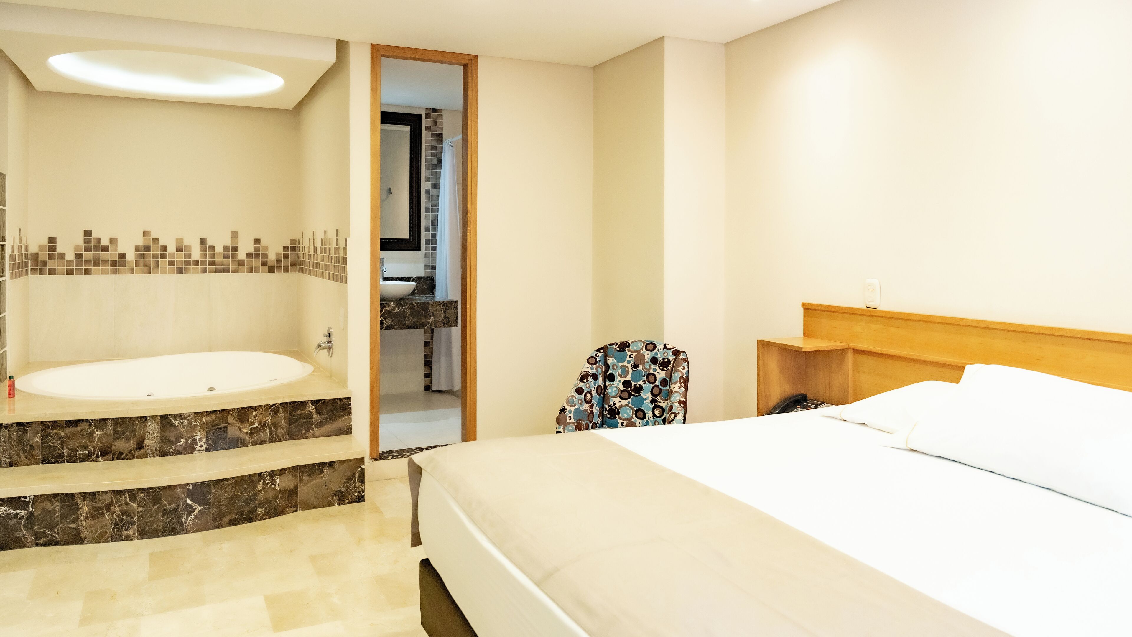 Une chambre d’hôtel avec un grand lit, une salle de bain séparée avec une baignoire et un petit coin salon.