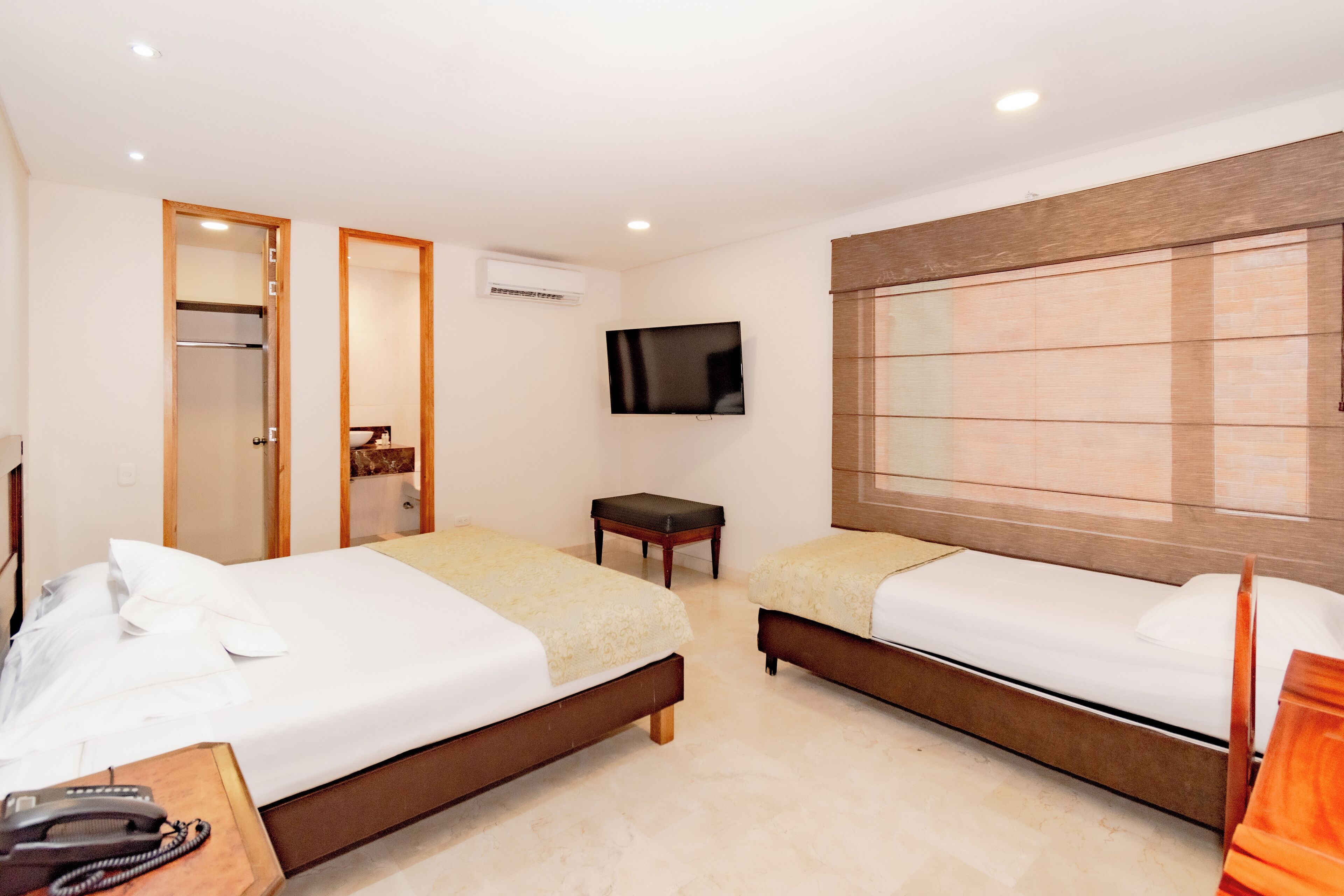 A hotel room with two beds, a TV, a mirror, a small table, and a telephone.