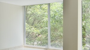 Un baño moderno con una bañera grande, un muro de listones de madera y vistas a zonas verdes a través de amplios ventanales.