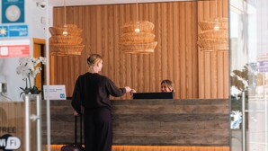 Un mostrador de recepción con un fondo de paneles de madera, un cartel que indica una zona de Wi-Fi gratuito y un área de recepción de diseño moderno.
