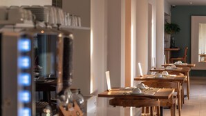Un comedor moderno con varias mesas, una cafetera y una planta en maceta.