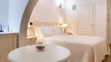 Une chambre d’hôtel avec un lit, une table de chevet avec une lampe, une table ronde avec un bol en verre et une porte.