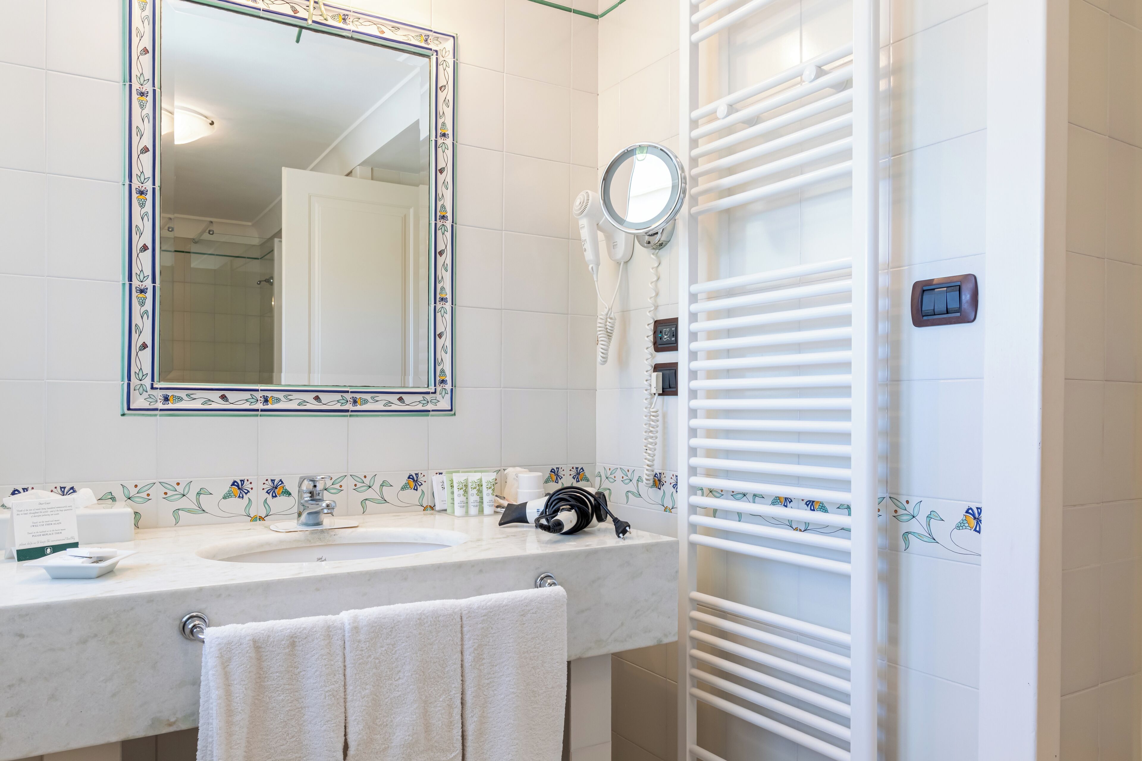 A bathroom with a white sink, a mirror, a hairdryer, and a towel rack.