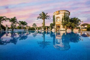 A pool with a reflection of a building and palm trees. - Sangiorgio Resort & Spa (Cutrofiano)