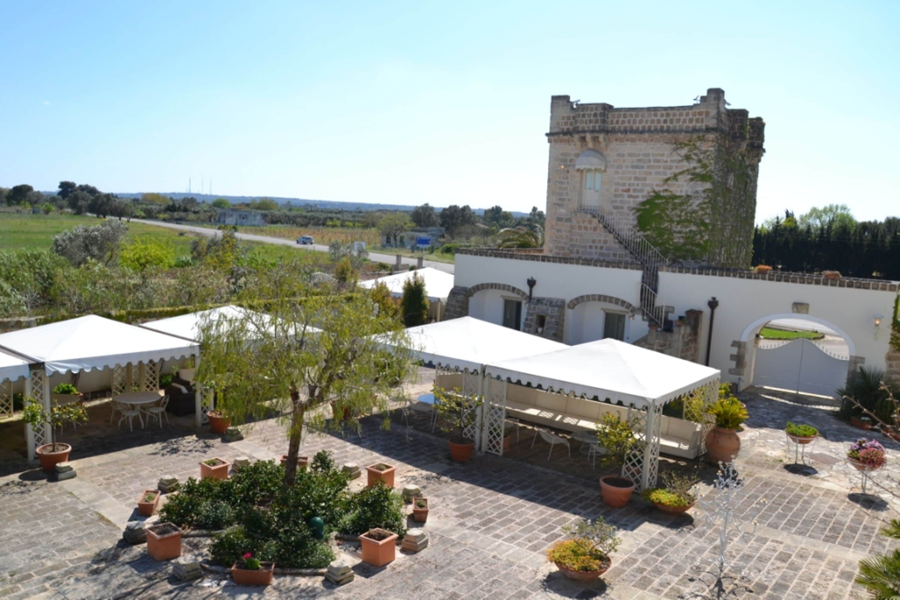 A courtyard with a stone tower, outdoor seating, and potted plants.