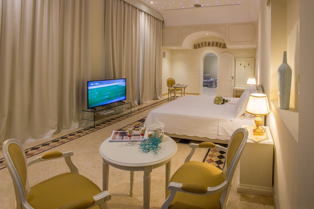 A hotel room with a bed, a television, a desk with a lamp, and a chair.