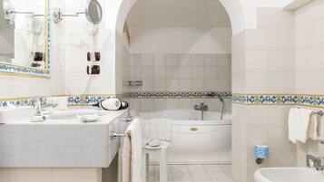 A bathroom with a sink, mirror, hairdryer, and bathtub.