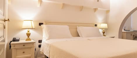 Una habitación de hotel con cama, mesitas de noche, lámparas y una lámpara fijada en la pared.