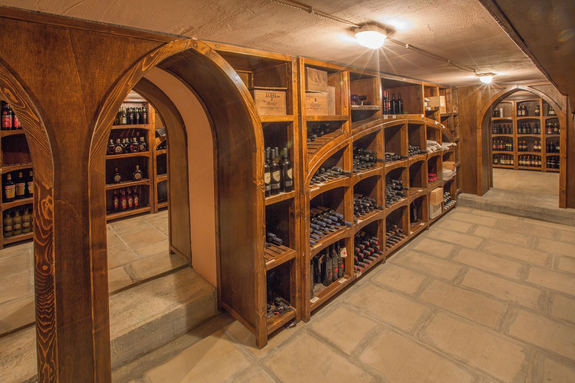 Una cantina vinicola con scaffali in legno e pavimento in pietra.