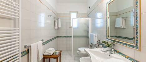 Un baño con ducha, inodoro, lavabo y una pequeña mesa con toallas.