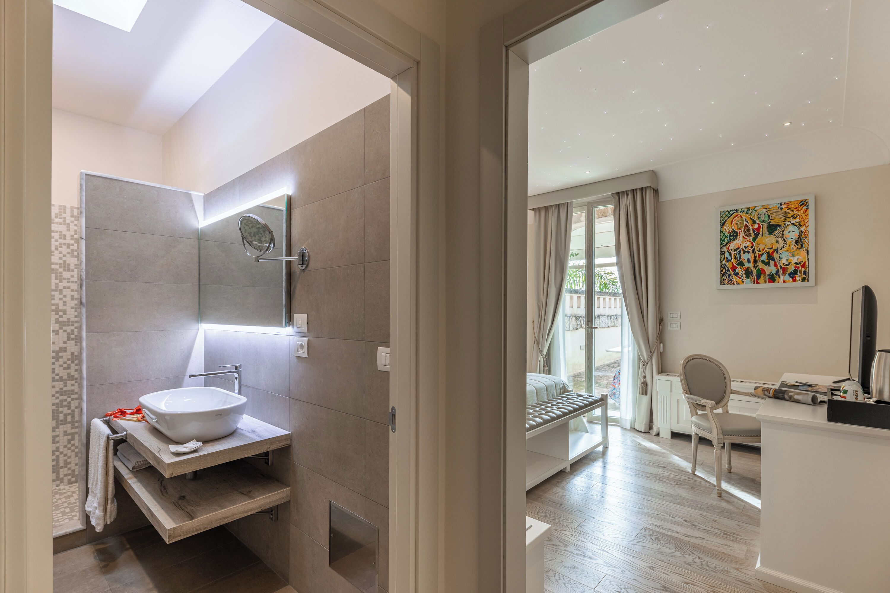 Un baño moderno con tragaluz, un espejo grande y un lavamanos blanco.