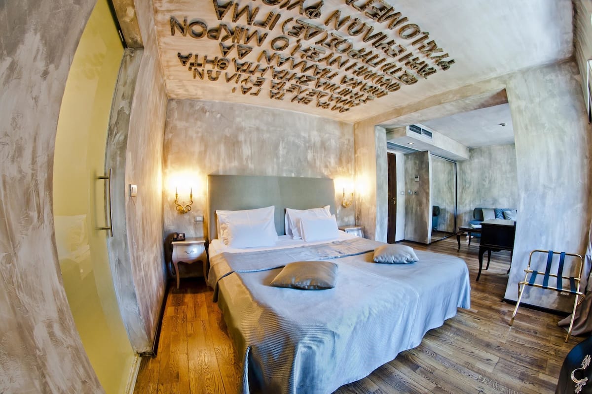 Une chambre à coucher avec un grand lit, des tables de chevet et un plafond orné de motifs textuels.