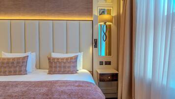 A hotel room with a large bed, a bedside lamp, a nightstand, and a window with curtains.
