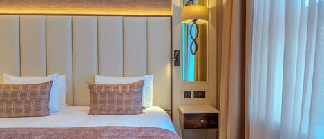 A hotel room with a large bed, a bedside lamp, a nightstand, and a window with curtains.