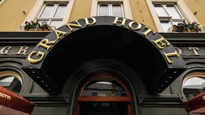 Entrada de un hotel con un arco negro y letras doradas que dicen "GRAND HOTEL".