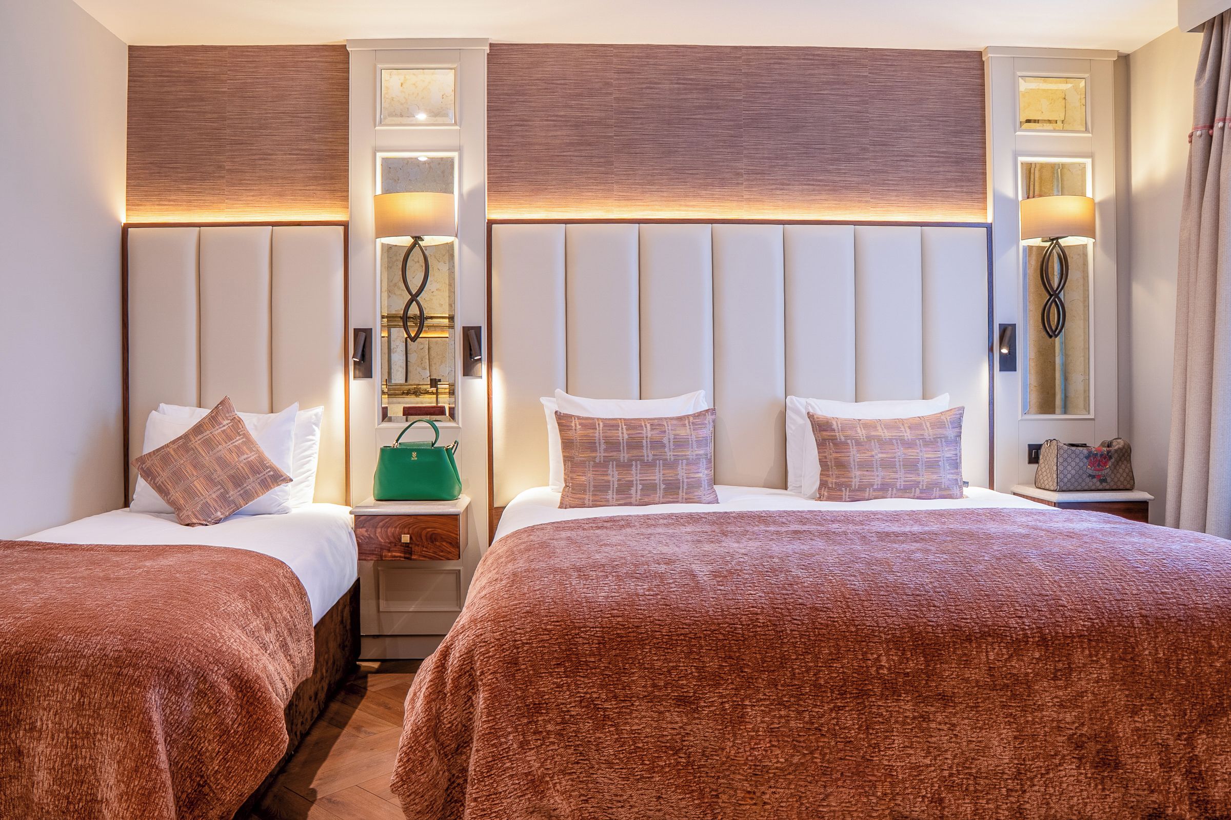 Habitación de hotel con dos camas, una mesita de noche, un espejo y una lámpara.