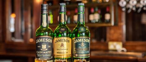 Three bottles of Jameson Irish whiskey on a wooden surface with shot glasses in front.