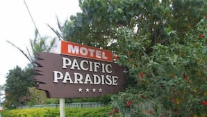 Un letrero de motel con el nombre 'Pacific Paradise' y una calificación de cinco estrellas.
