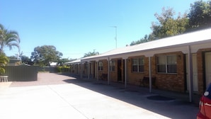 Filas de habitaciones de motel de una sola planta, con un área exterior techada y un estacionamiento de grava.