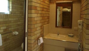 A bathroom with a tiled wall, a sink, a mirror, and a telephone. - Pacific Paradise Motel (Pacific Paradise)