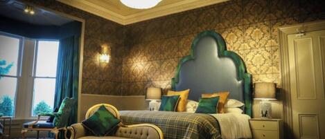 A bedroom with a large bed, a nightstand, a chair, and a window with curtains.