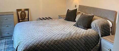 Un dormitorio con una cama grande, una mesita de noche, una lámpara de pared y un cuadro en la pared.