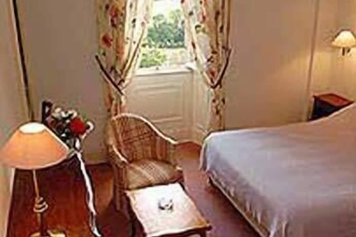 Ein Schlafzimmer mit einem Bett, einem Sessel, einem kleinen Tisch und einer Lampe.