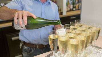 A person pouring champagne into several glasses on a tray.