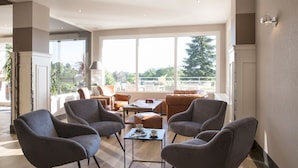 A spacious living area with modern furniture, large windows, and a view of the outdoors.