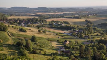 Paisagem rural com casas dispersas, vinhedos e colinas ondulantes.
