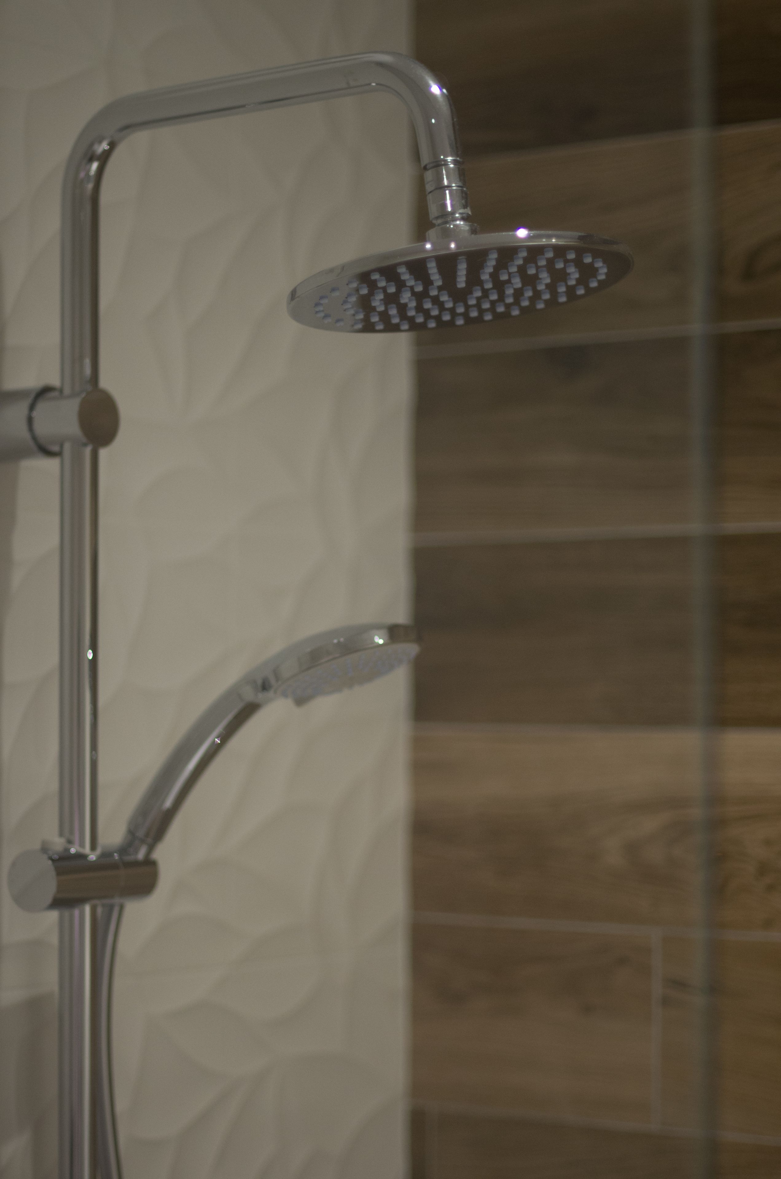 Une douche équipée d’un pommeau de douche à main et d’un pommeau de douche fixe.