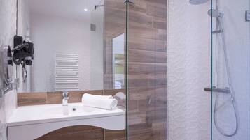 A modern bathroom with a glass-enclosed shower, a white sink, and a towel on the counter.