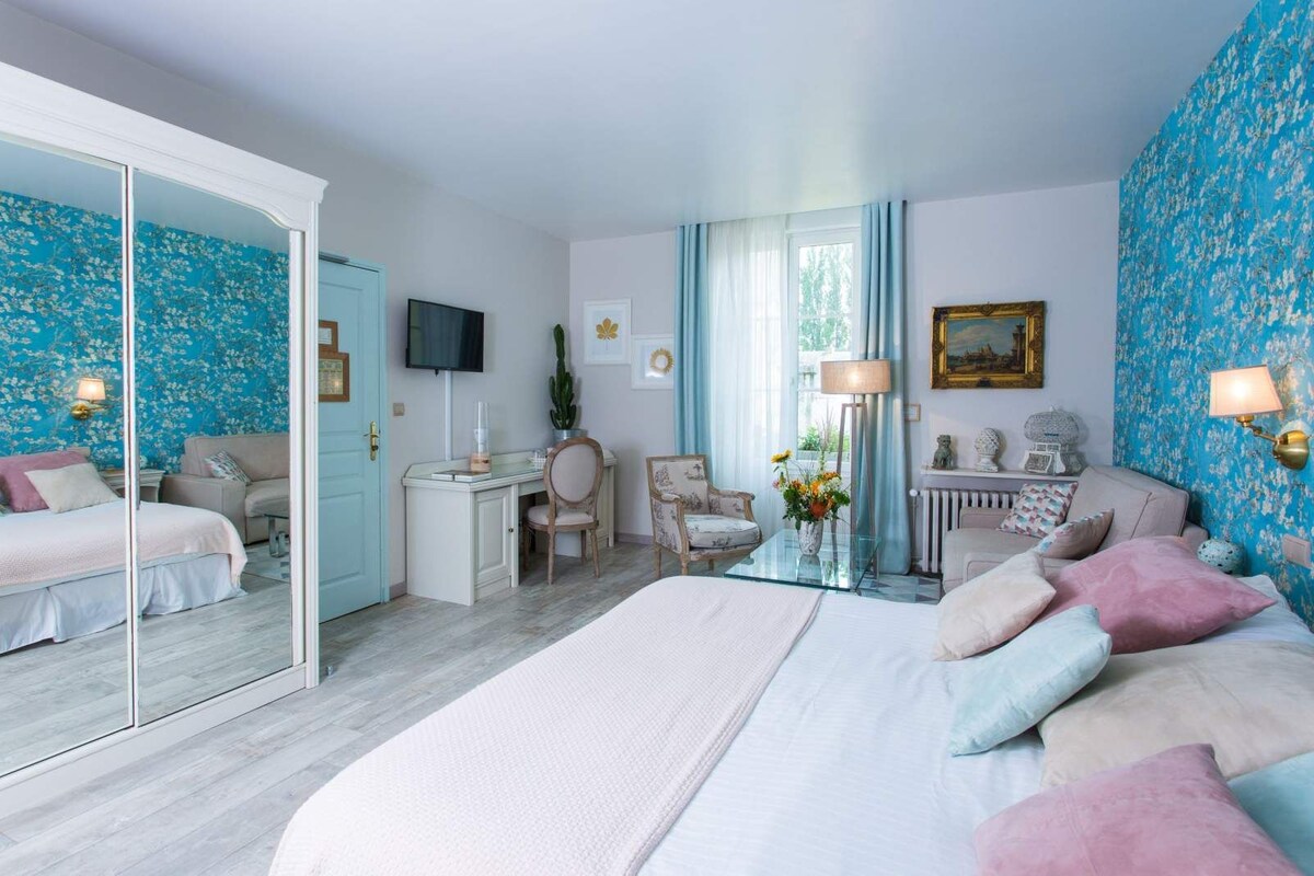 Une chambre d’hôtel avec un grand lit, un bureau, une chaise, un canapé, un miroir et une télévision.